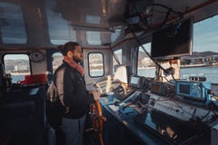 Молодое Capitan с бородой стоит на кормиле и контролирует корабль, взгляд изнутри кабины ` s капитана стоковые фотографии rf Молодое Capitan с бородой стоит на кормиле и контролирует корабль, взгляд изнутри кабины ` s капитана стоковые фотографии rf