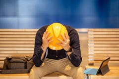 Молодое азиатское попробованное чувство человека инженера пока сидящ на стенде Стоковые Изображения Молодое азиатское попробованное чувство человека инженера пока сидящ на стенде Стоковые Изображения