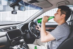 Молодой азиатский человек управляет автомобилем с пьяным бутылка пива за рулем автомобиля стоковая фотография Молодой азиатский человек управляет автомобилем с пьяным бутылка пива за рулем автомобиля стоковая фотография