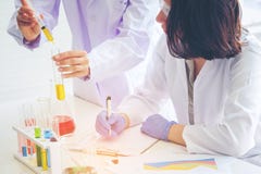 Молодой женский ученый стоя с techer в делать работника лаборатории стоковое фото Молодой женский ученый стоя с techer в делать работника лаборатории стоковое фото