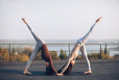 2 молодой женщины делая смотреть на asana йоги партнера вниз - собаку Стоковое Изображение 2 молодой женщины делая смотреть на asana йоги партнера вниз - собаку Стоковое Изображение