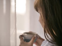 Молодой кофе утра напитков девушки брюнета смотря вне окно стоковые изображения Молодой кофе утра напитков девушки брюнета смотря вне окно стоковые изображения