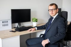 Молодой красивый бизнесмен сидя в современном офисе стоковое изображение Молодой красивый бизнесмен сидя в современном офисе стоковое изображение