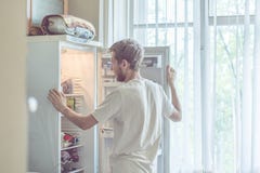 Молодой красивый бородатый человек стоя около opended кухни холодильника дома стоковое изображение rf Молодой красивый бородатый человек стоя около opended кухни холодильника дома стоковое изображение rf