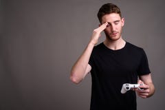 Молодой красивый человек играя игры против серой предпосылки стоковое изображение Молодой красивый человек играя игры против серой предпосылки стоковое изображение