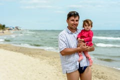 Молодой отец в солнечных очках на пляже с маленькой дочерью стоковая фотография Молодой отец в солнечных очках на пляже с маленькой дочерью стоковая фотография