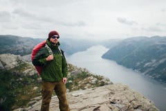 Молодой парень с рюкзаком наслаждаясь заходом солнца на пике туманного mountai стоковая фотография Молодой парень с рюкзаком наслаждаясь заходом солнца на пике туманного mountai стоковая фотография