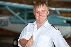 Молодой пилот при Синдром Дауна показывая большие пальцы руки вверх. стоковое изображение rf Молодой пилот при Синдром Дауна показывая большие пальцы руки вверх. стоковое изображение rf