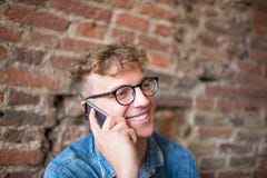 Молодой усмехаясь парень битника говоря на портативном мобильном телефоне стоковые фотографии rf Молодой усмехаясь парень битника говоря на портативном мобильном телефоне стоковые фотографии rf