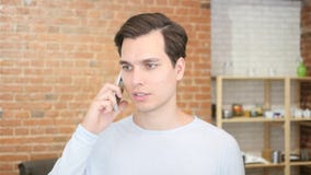 молодой человек в офисе на телефоне с шлемофоном, видео- болтовней стоковые изображения rf молодой человек в офисе на телефоне с шлемофоном, видео- болтовней стоковые изображения rf