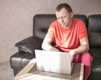 Молодой человек сидя около ноутбука в его живущей комнате на солнечном после полудня, copyspace стоковые фотографии rf Молодой человек сидя около ноутбука в его живущей комнате на солнечном после полудня, copyspace стоковые фотографии rf