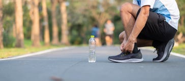 Молодой человек спортсмена связывая идущие ботинки в парке внешнем мужской бегун готовый для jogging на дороге снаружи Азиатская стоковая фотография rf Молодой человек спортсмена связывая идущие ботинки в парке внешнем мужской бегун готовый для jogging на дороге снаружи Азиатская стоковая фотография rf