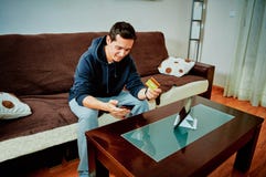 Молодые видеоигры приобретения мальчика над интернетом с его мобильным телефоном стоковое изображение Молодые видеоигры приобретения мальчика над интернетом с его мобильным телефоном стоковое изображение