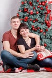 Молодые и счастливые пары семьи сидя около украшенного дерева Нового Года женщина портрета стороны крупного плана Стоковые Изображения RF Молодые и счастливые пары семьи сидя около украшенного дерева Нового Года женщина портрета стороны крупного плана Стоковые Изображения RF