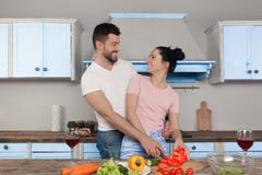 Молодые красивые пары обнимая в кухне варя совместно салат Они усмехаются на одине другого стоковое фото Молодые красивые пары обнимая в кухне варя совместно салат Они усмехаются на одине другого стоковое фото