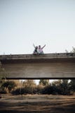Молодые пары в любов поднимая их руки на старом мосте стоковая фотография Молодые пары в любов поднимая их руки на старом мосте стоковая фотография