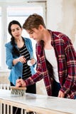 Молодые пары деля инструменты пока работающ на улучшении их нового дома Стоковая Фотография Молодые пары деля инструменты пока работающ на улучшении их нового дома Стоковая Фотография