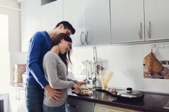 Молодые пары на кухне обнимая и варя обедающий стоковые фото Молодые пары на кухне обнимая и варя обедающий стоковые фото