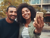 Молодые пары принимая selfie на мобильном телефоне стоковая фотография rf Молодые пары принимая selfie на мобильном телефоне стоковая фотография rf