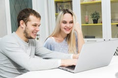 Молодые пары сидя на утре в их кухня и используя ноутбук E Современная кухня внутри стоковая фотография Молодые пары сидя на утре в их кухня и используя ноутбук E Современная кухня внутри стоковая фотография