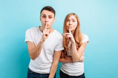 Молодые пары, человек и женщина, держа пальцы на губах рта, Hush, секрет, показывая shhs, на голубой предпосылке стоковые фото Молодые пары, человек и женщина, держа пальцы на губах рта, Hush, секрет, показывая shhs, на голубой предпосылке стоковые фото