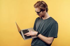 Молодые привлекательные стекла Гая нося используя компьтер-книжку стоковое изображение rf Молодые привлекательные стекла Гая нося используя компьтер-книжку стоковое изображение rf