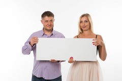 Молодые радостные пары показывая представление указывая плакат стоковая фотография Молодые радостные пары показывая представление указывая плакат стоковая фотография