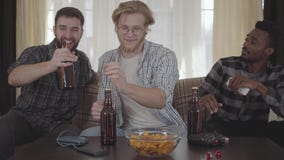 3 молодых счастливых друз выпивая пиво и говоря дома совместно сток-видео 3 молодых счастливых друз выпивая пиво и говоря дома совместно сток-видео