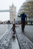 Мост башни на заднем плане, принятый на больше Лондона на южном береге На переднем плане запачканный ребенок играя в воде стоковые изображения rf Мост башни на заднем плане, принятый на больше Лондона на южном береге На переднем плане запачканный ребенок играя в воде стоковые изображения rf