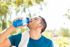 Мужская питьевая вода спортсмена после разминки в парке стоковое фото Мужская питьевая вода спортсмена после разминки в парке стоковое фото