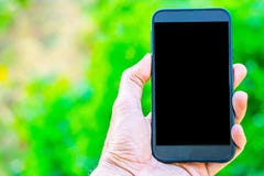 Мужская рука держа smartphone на предпосылке bokeh дерева используя обои или предпосылке для работы связи стоковые изображения Мужская рука держа smartphone на предпосылке bokeh дерева используя обои или предпосылке для работы связи стоковые изображения