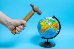 Мужская рука со старым ржавым молотком, качания над глобусом стоковые изображения rf Мужская рука со старым ржавым молотком, качания над глобусом стоковые изображения rf