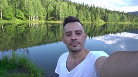 Мужское принимая фото около красивого ландшафта, лес selfie около озера сток-видео Мужское принимая фото около красивого ландшафта, лес selfie около озера сток-видео