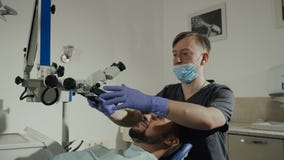 Мужской дантист с зубоврачебными инструментами в клинике - микроскопе, зеркале и зонде обрабатывая терпеливые зубы на зубоврачебн видеоматериал Мужской дантист с зубоврачебными инструментами в клинике - микроскопе, зеркале и зонде обрабатывая терпеливые зубы на зубоврачебн видеоматериал