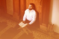 Мусульманский человек читая святую исламскую книгу Koran стоковые фотографии rf Мусульманский человек читая святую исламскую книгу Koran стоковые фотографии rf