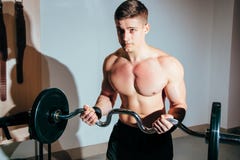 Мышечный человек разрабатывая в спортзале делая тренировки с штангой, сильным мужским нагим abs торса стоковая фотография Мышечный человек разрабатывая в спортзале делая тренировки с штангой, сильным мужским нагим abs торса стоковая фотография