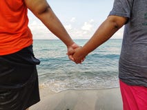 На пляже любовники держа руки для того чтобы идти вниз к морю r стоковое фото rf На пляже любовники держа руки для того чтобы идти вниз к морю r стоковое фото rf