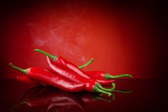 Накаленный докрасна chili на красной предпосылке с дымом Стоковые Фотографии RF Накаленный докрасна chili на красной предпосылке с дымом Стоковые Фотографии RF