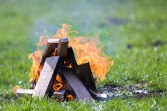 Накаляя костер на природе Горящие деревянные планки снаружи на летний день Яркие оранжевые пламена, светлый дым и темные золы на стоковое изображение Накаляя костер на природе Горящие деревянные планки снаружи на летний день Яркие оранжевые пламена, светлый дым и темные золы на стоковое изображение