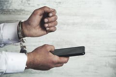 Наручники и телефон руки человека стоковые изображения rf Наручники и телефон руки человека стоковые изображения rf