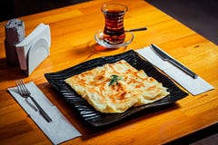 Национальное блюдо в черной стильной плите и стекле черного турецкого чая на деревянном столе стоковое изображение Национальное блюдо в черной стильной плите и стекле черного турецкого чая на деревянном столе стоковое изображение