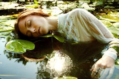 Нежное заплывание молодой женщины в пруде среди лилий воды стоковые фото Нежное заплывание молодой женщины в пруде среди лилий воды стоковые фото