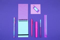 Неоновые розовые канцелярские принадлежности на предпосылке сирени стоковые изображения rf Неоновые розовые канцелярские принадлежности на предпосылке сирени стоковые изображения rf