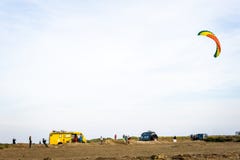 Непознаваемые люди летая змей прибоя на пляже с фургонами на заднем плане стоковое изображение Непознаваемые люди летая змей прибоя на пляже с фургонами на заднем плане стоковое изображение