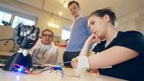 Неработающая женщина двигает ее ампутированную руку и рука робота делает некоторые движения Инженеры контролировать акции видеоматериалы Неработающая женщина двигает ее ампутированную руку и рука робота делает некоторые движения Инженеры контролировать акции видеоматериалы