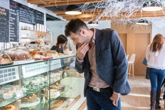 Нерешительный человек смотря различные торты, который подвергли действию в витрину Стоковые Фото Нерешительный человек смотря различные торты, который подвергли действию в витрину Стоковые Фото