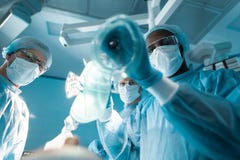 нижний взгляд Афро-американского anesthetist держа кислородный изолирующий противогаз стоковые фотографии rf нижний взгляд Афро-американского anesthetist держа кислородный изолирующий противогаз стоковые фотографии rf