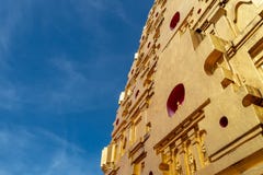 Низкий угол красивого золотого стального виска с небольшой статуей Будды на предпосылке голубого неба стоковое фото rf Низкий угол красивого золотого стального виска с небольшой статуей Будды на предпосылке голубого неба стоковое фото rf