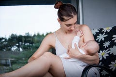 Новая мама держа ее маленького сына и кормя грудью, нянча младенец стоковые изображения Новая мама держа ее маленького сына и кормя грудью, нянча младенец стоковые изображения
