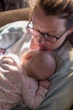 Новая мать и младенец дома спать на кресле в свете утра стоковые фото Новая мать и младенец дома спать на кресле в свете утра стоковые фото